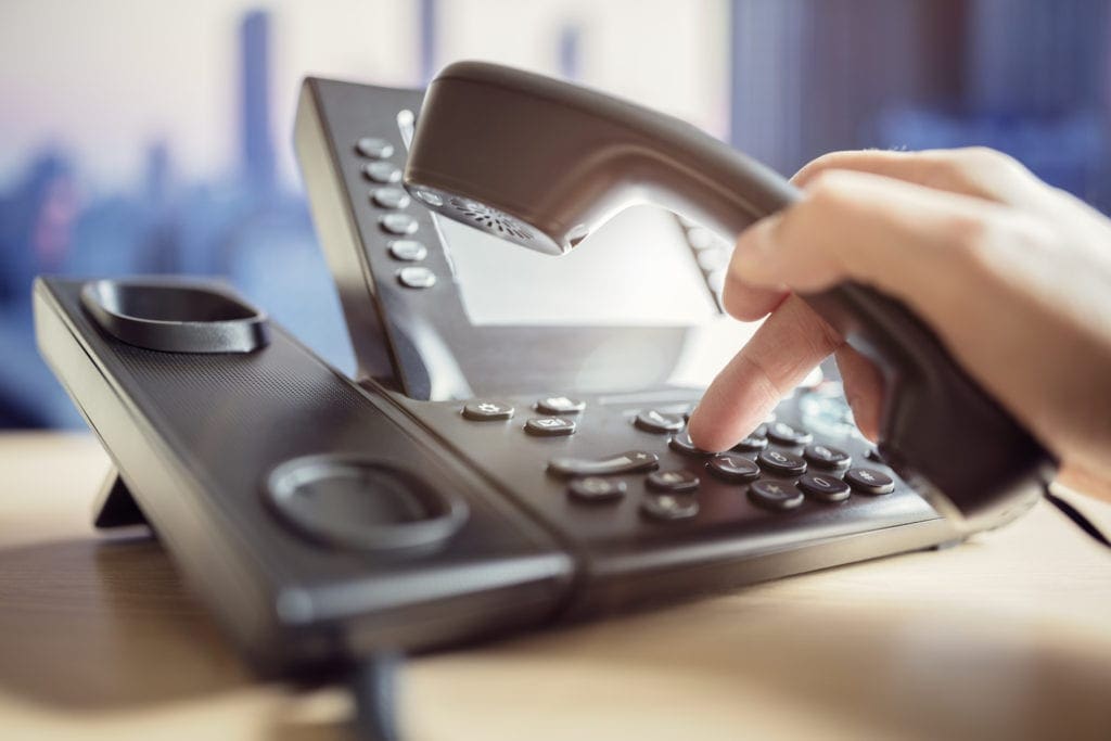 The Ultimate Guide To Small Business Phone Systems 1 Person Dialing A Call On A Business Phone System.